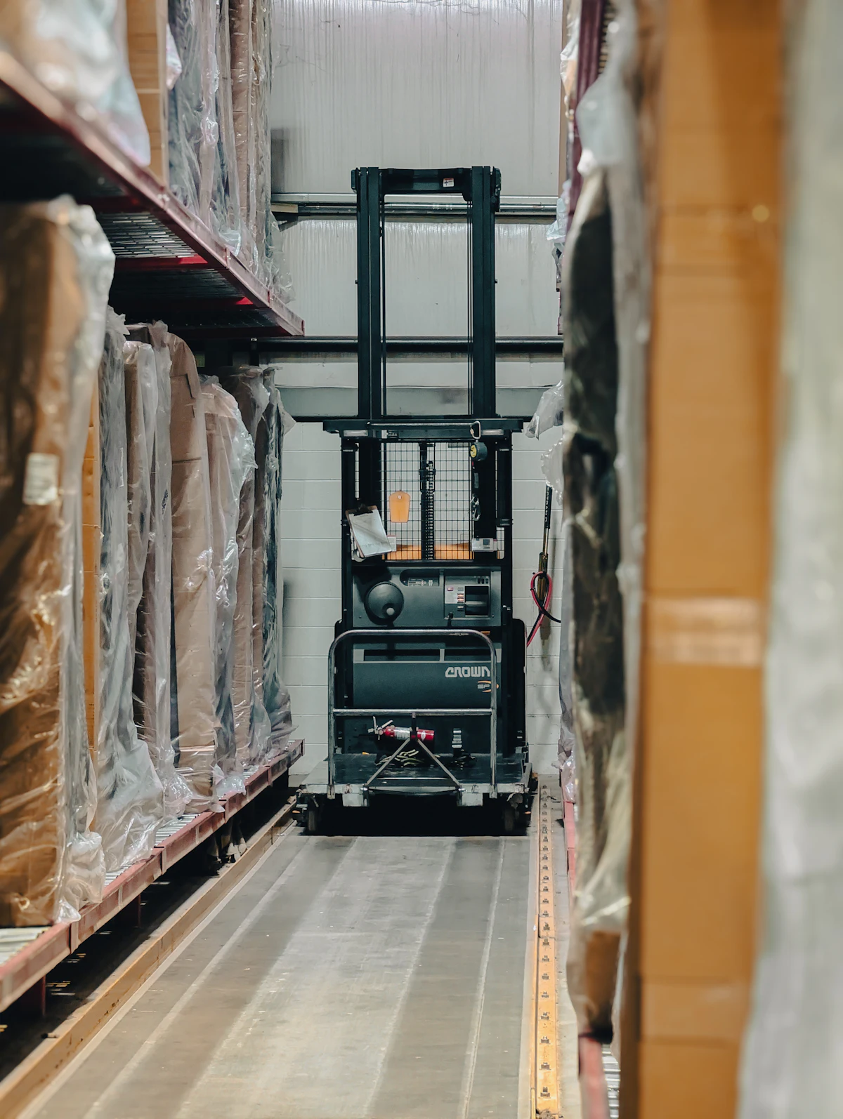 Warehouse aisle with stocked pallets and a forklift